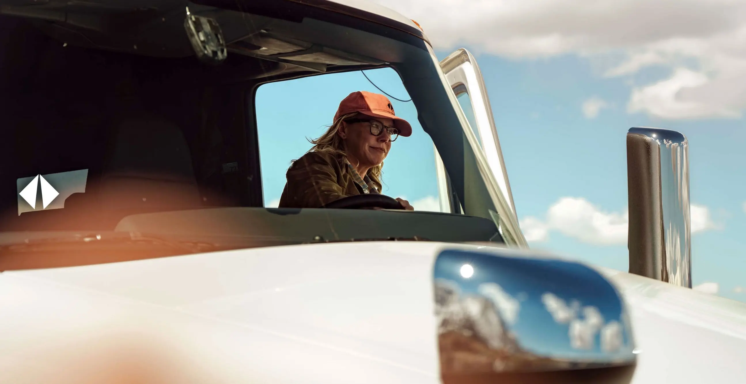Seis Grados Estrategia y Diseño | Conductor observa el horizonte desde la cabina de un camión naranja de Sierra Norte al amanecer. 